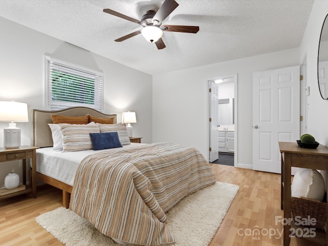bedroom with a textured ceiling, ceiling fan, connected bathroom, and light wood finished floors