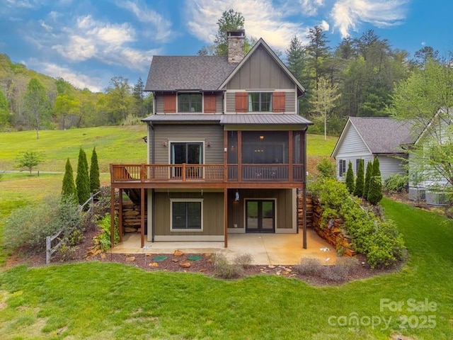 rear view of property featuring stairs, a wooden deck, board and batten siding, a chimney, and a patio area