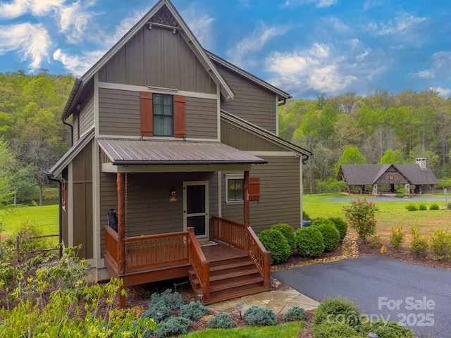 back of property featuring covered porch, board and batten siding, and a forest view