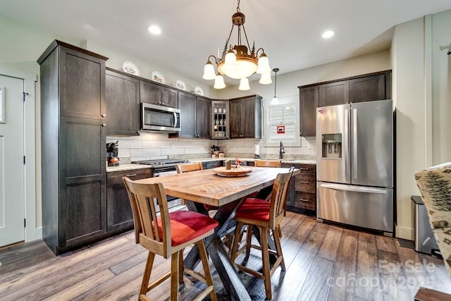 kitchen featuring appliances with stainless steel finishes, tasteful backsplash, dark brown cabinetry, and hardwood / wood-style floors