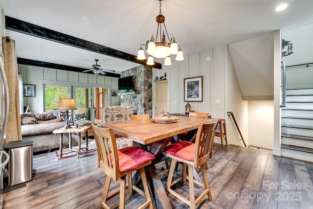 dining area with stairway, beamed ceiling, ceiling fan with notable chandelier, and dark wood finished floors