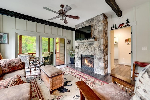 living room featuring beamed ceiling, ceiling fan, wood finished floors, and a fireplace