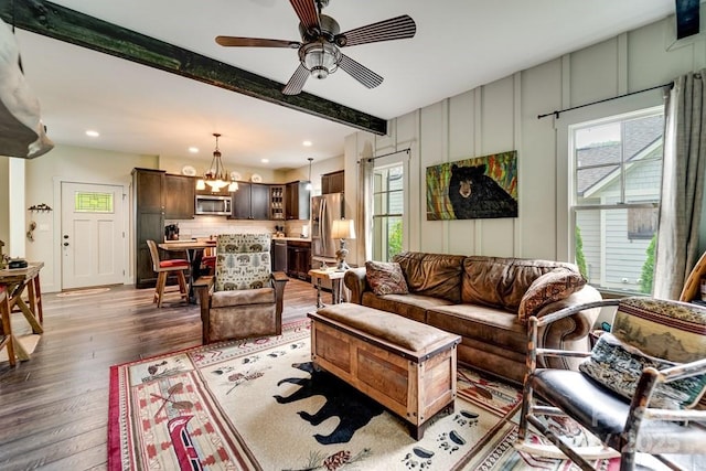 living area featuring beam ceiling, ceiling fan with notable chandelier, recessed lighting, and wood finished floors