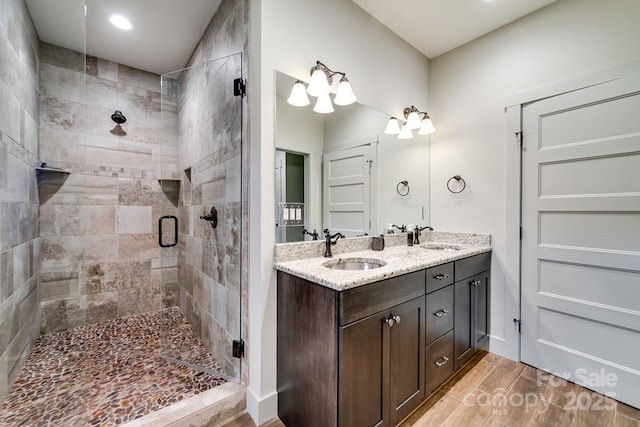 full bath featuring wood finished floors, a sink, a stall shower, and double vanity