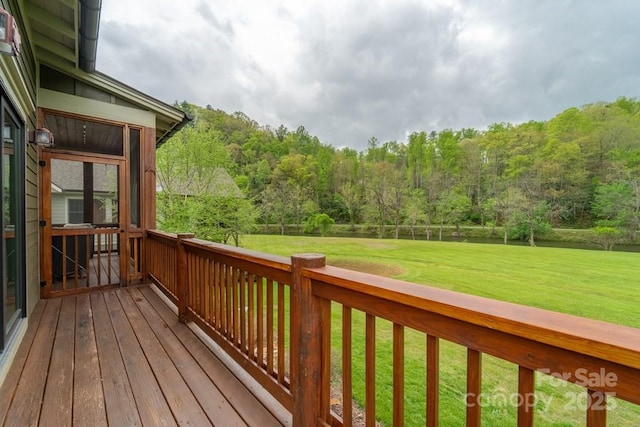 wooden terrace with a yard and a wooded view