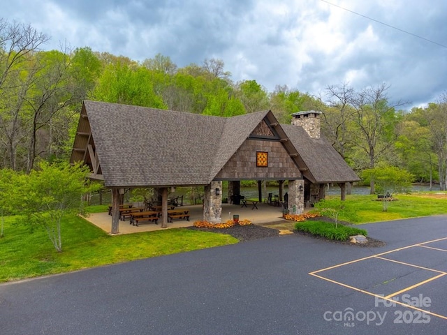 view of home's community with a gazebo, uncovered parking, a lawn, and a forest view