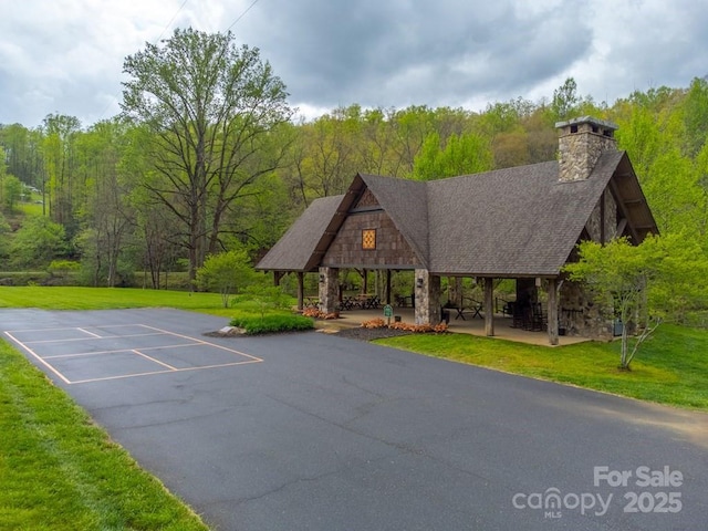 view of home's community featuring a gazebo, uncovered parking, a yard, and a wooded view