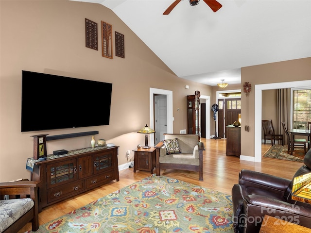 living room with ceiling fan, baseboards, high vaulted ceiling, and light wood-type flooring
