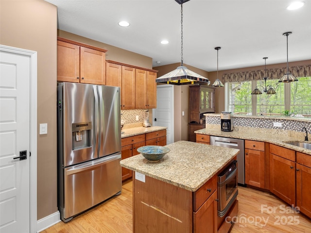 kitchen with tasteful backsplash, a center island, light wood-style floors, and appliances with stainless steel finishes