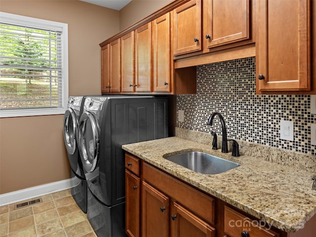 laundry area featuring washing machine and dryer, a sink, visible vents, baseboards, and cabinet space