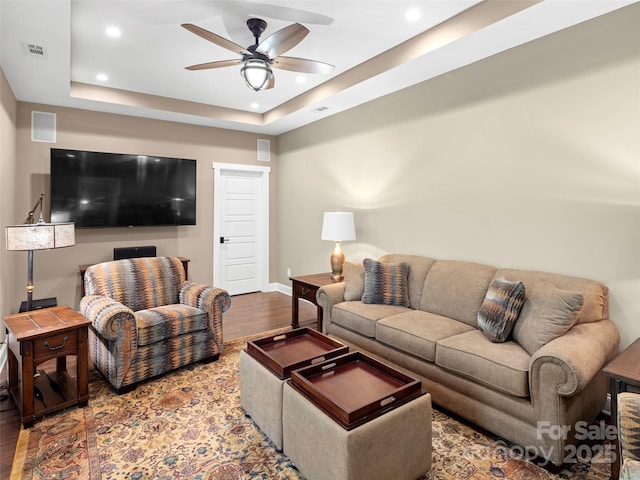 living room with recessed lighting, a tray ceiling, a ceiling fan, baseboards, and wood finished floors