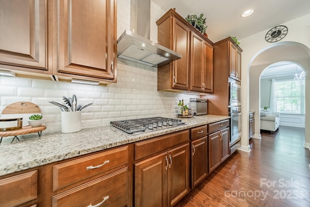 16507 Palisades Commons Dr, Charlotte, NC 28278 - kitchen with wall chimney exhaust hood, appliances with stainless steel finishes, arched walkways, baseboards, and light stone counters