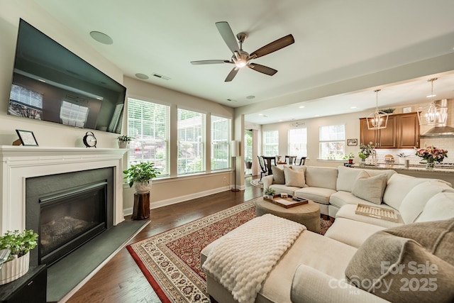 16507 Palisades Commons Dr, Charlotte, NC 28278 - living room featuring dark wood-style flooring, a ceiling fan, a glass covered fireplace, baseboards, and a chandelier