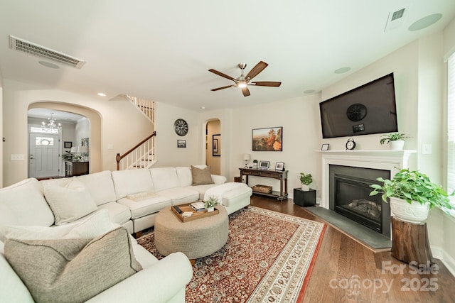 16507 Palisades Commons Dr, Charlotte, NC 28278 - living area with arched walkways, stairs, wood finished floors, a glass covered fireplace, and ceiling fan