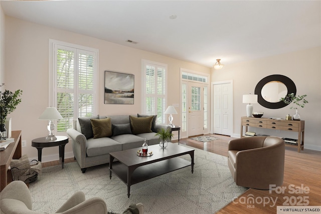 living room with baseboards, visible vents, and wood finished floors
