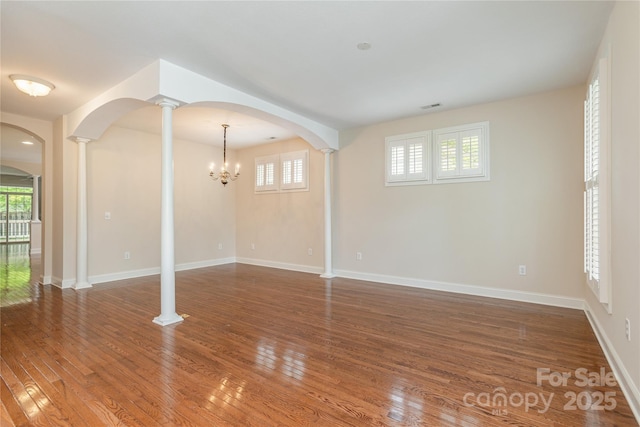 unfurnished living room with visible vents, arched walkways, and a wealth of natural light