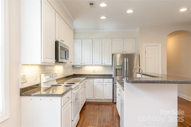 kitchen featuring visible vents, wood finished floors, a center island with sink, arched walkways, and appliances with stainless steel finishes