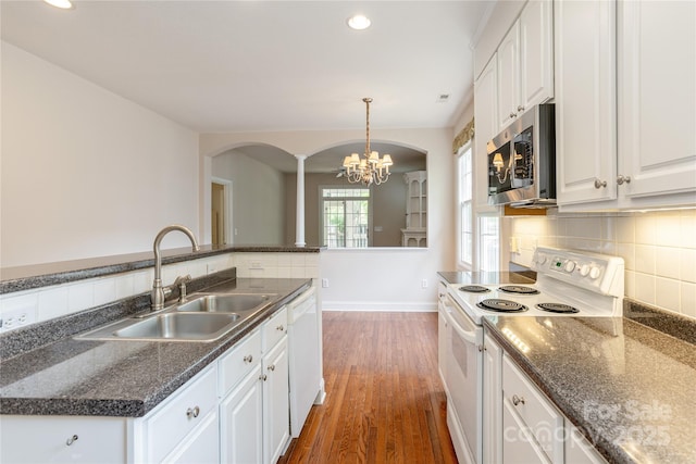 kitchen with decorative columns, arched walkways, a sink, white cabinets, and white appliances