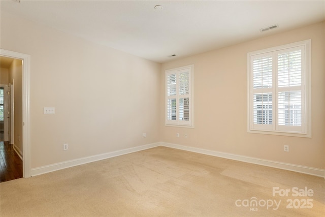 unfurnished room with carpet flooring, baseboards, and visible vents