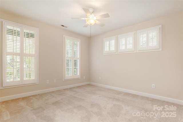 carpeted empty room with baseboards, ceiling fan, and visible vents