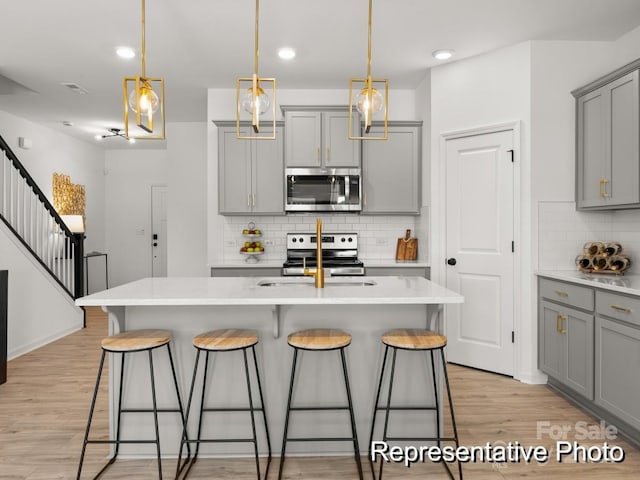 kitchen featuring a sink, a kitchen bar, gray cabinets, and stainless steel appliances