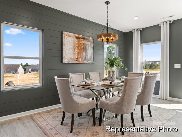 dining room featuring baseboards, a healthy amount of sunlight, light wood finished floors, and an inviting chandelier