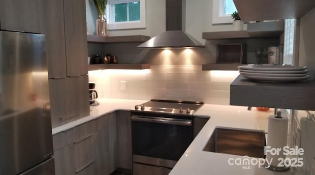kitchen featuring appliances with stainless steel finishes, wall chimney range hood, open shelves, and modern cabinets
