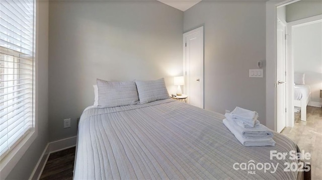 bedroom with baseboards, wood finished floors, and multiple windows