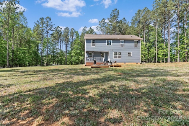 rear view of house with a lawn, a wooden deck, crawl space, and a forest view