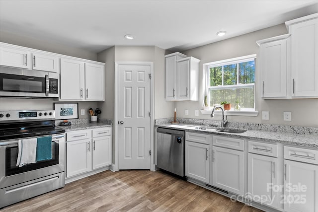 kitchen featuring a sink, appliances with stainless steel finishes, light wood-type flooring, and white cabinetry