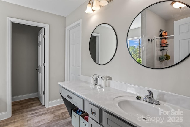 bathroom with baseboards, wood finished floors, and vanity