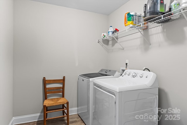washroom featuring washer and dryer, laundry area, baseboards, and wood finished floors
