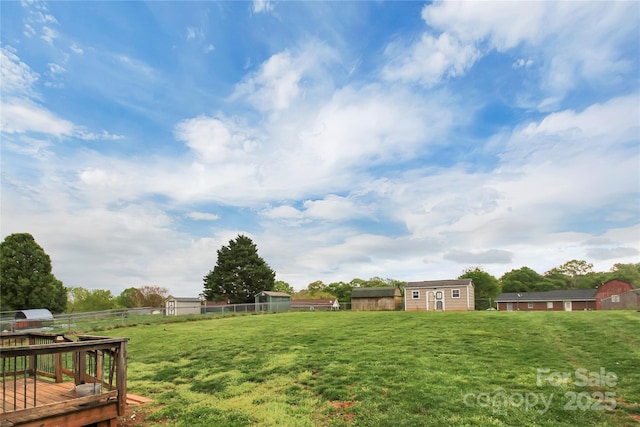view of yard featuring an outdoor structure, a shed, a wooden deck, and fence