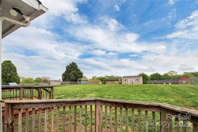 view of yard with a deck, a storage unit, fence, and an outbuilding