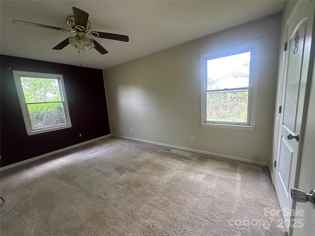 carpeted empty room with ceiling fan and baseboards