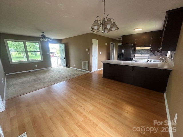 kitchen featuring fridge with ice dispenser, a sink, under cabinet range hood, visible vents, and electric range