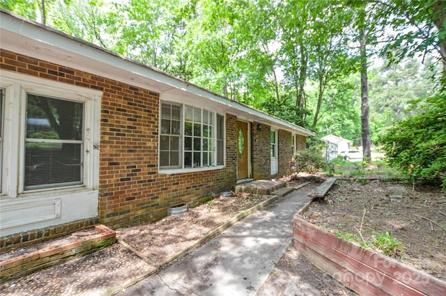 view of side of property with brick siding, crawl space, and entry steps