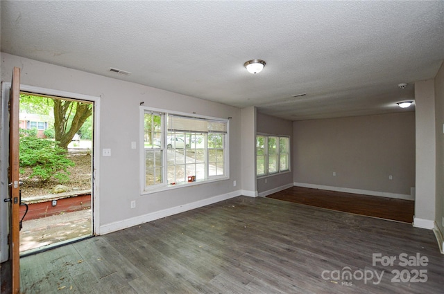 unfurnished living room featuring baseboards, visible vents, plenty of natural light, and wood finished floors