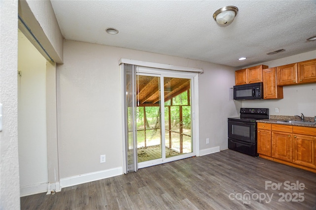 kitchen featuring dark wood finished floors, baseboards, black appliances, and a sink