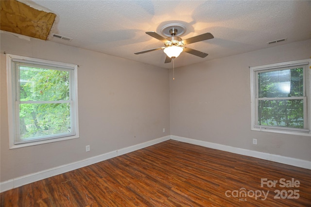 empty room featuring baseboards, visible vents, and wood finished floors