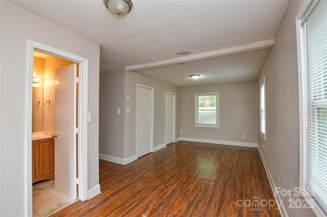 empty room with a textured ceiling, wood finished floors, and baseboards