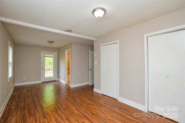 interior space with a textured ceiling, baseboards, and wood finished floors