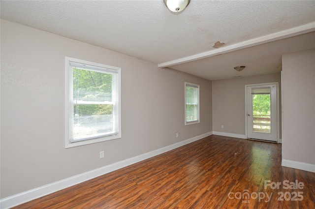 spare room featuring baseboards, a wealth of natural light, a textured ceiling, and wood finished floors