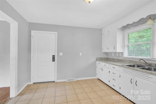 kitchen with visible vents, a sink, light countertops, baseboards, and white cabinetry