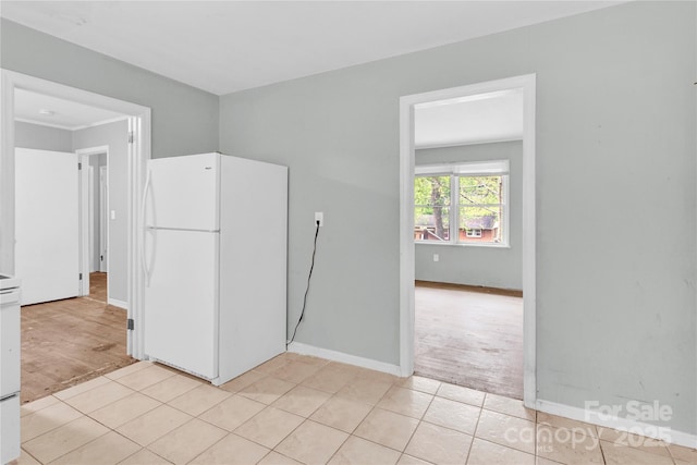kitchen featuring light tile patterned floors, baseboards, and freestanding refrigerator