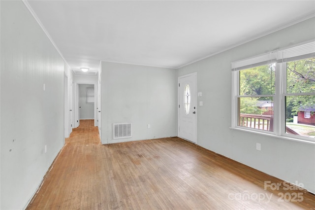 unfurnished living room featuring ornamental molding, light wood finished floors, and visible vents