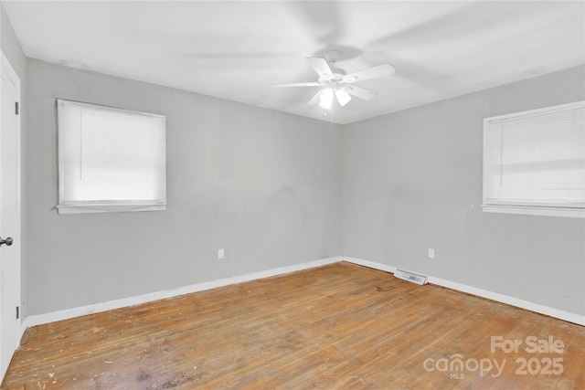 spare room featuring baseboards, a ceiling fan, hardwood / wood-style flooring, and visible vents