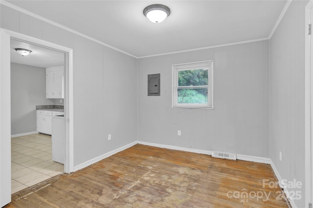 unfurnished room featuring visible vents, ornamental molding, baseboards, light wood-type flooring, and electric panel