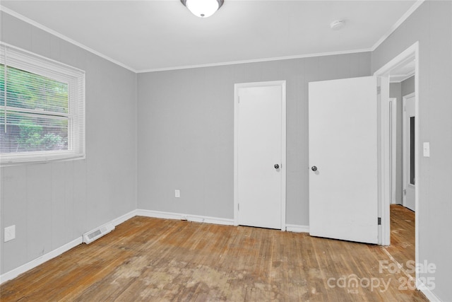 unfurnished bedroom with visible vents, ornamental molding, and hardwood / wood-style floors