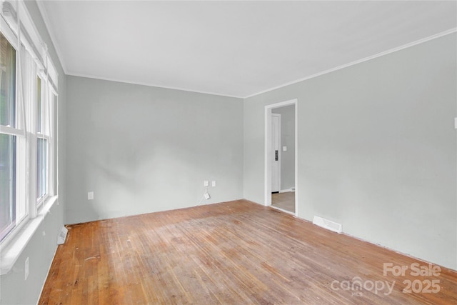 spare room featuring crown molding, visible vents, and wood finished floors